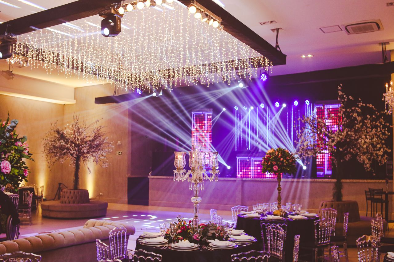 Stunning ballroom setup decorated with crystal chandeliers, floral arrangements, and vibrant stage lighting.
