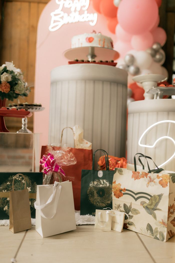 A beautifully decorated birthday setup featuring gifts, a cake, and balloons in a festive indoor setting.